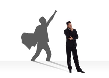 Concentrated businessman casting shadow of superhero on white background. Success, confidence, power and determination concepts