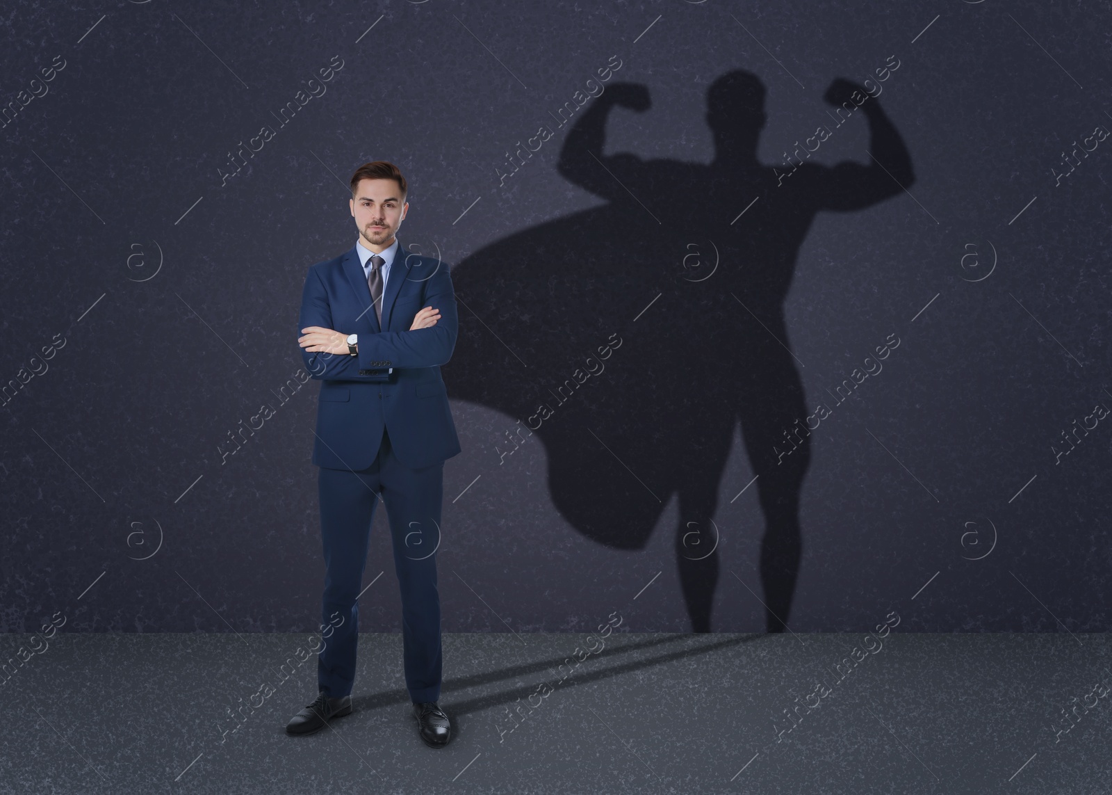 Image of Confident businessman casting shadow of superhero on grey background. Success, power, leadership and determination concepts