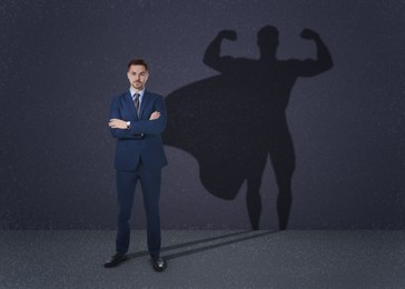 Image of Confident businessman casting shadow of superhero on grey background. Success, power, leadership and determination concepts