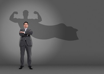 Confident businessman casting shadow of superhero on grey background. Success, power, leadership and determination concepts