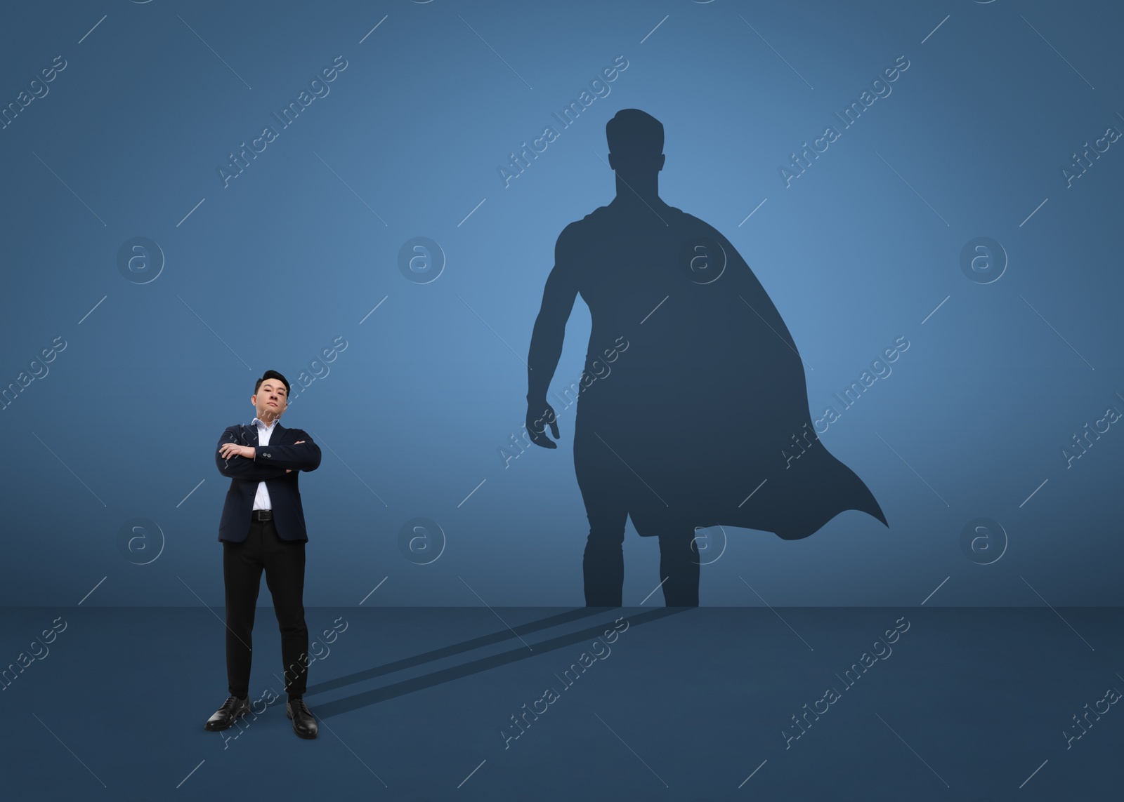 Image of Confident businessman casting shadow of superhero on light blue background. Success, power, leadership and determination concepts