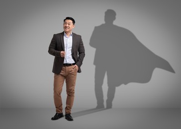 Confident businessman casting shadow of superhero on grey background. Success, power, leadership and determination concepts