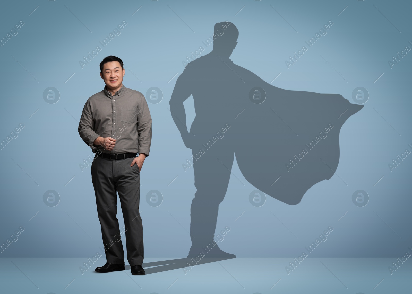 Image of Confident businessman casting shadow of superhero on light blue background. Success, power, leadership and determination concepts