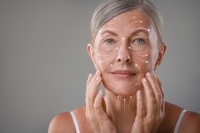 Beautiful woman with healthy skin on grey background. Arrows on face showing direction of massage moves