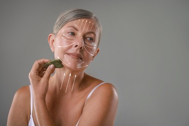 Image of Beautiful woman doing facial massage with gua sha tool on grey background. Arrows on skin showing direction of moves