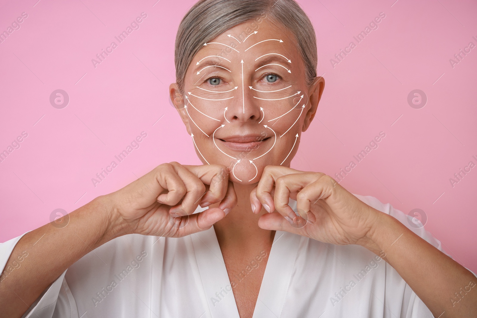 Image of Beautiful woman doing facial massage on pink background. Arrows on skin showing direction of moves