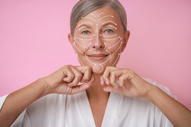 Image of Beautiful woman doing facial massage on pink background. Arrows on skin showing direction of moves