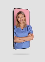 Online doctor standing out of mobile phone screen on light grey background