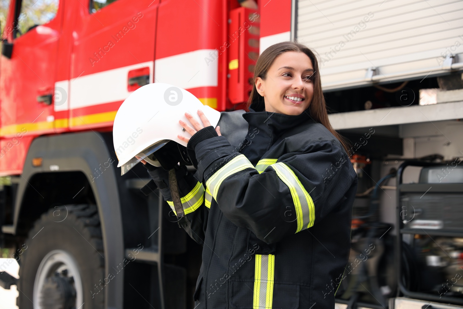 Photo of Portrait of firefighter in uniform with helmet near fire truck