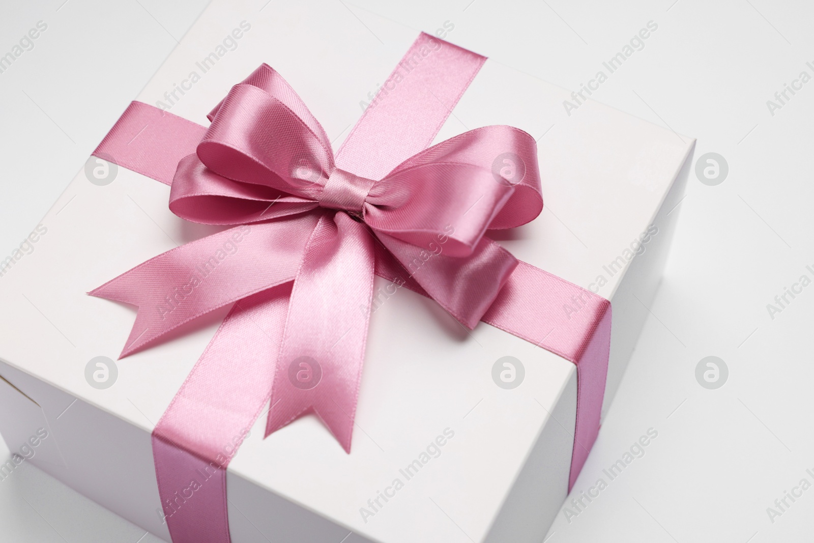 Photo of Gift box with pink bow on light grey background, closeup