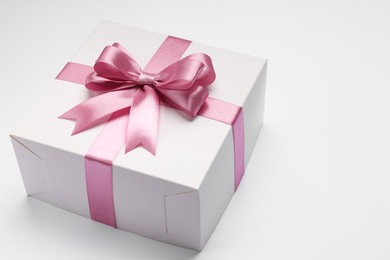 Photo of Gift box with pink bow on light grey background. Space for text