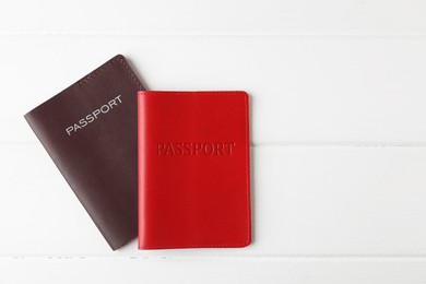 Photo of Passports on white wooden table, flat lay. Space for text