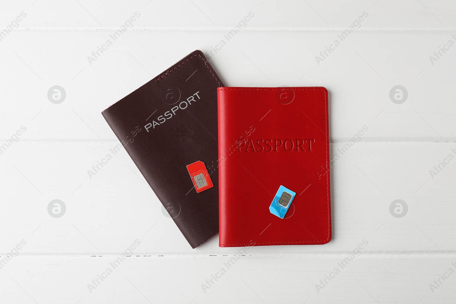 Photo of Passports and SIM cards on white wooden table, flat lay