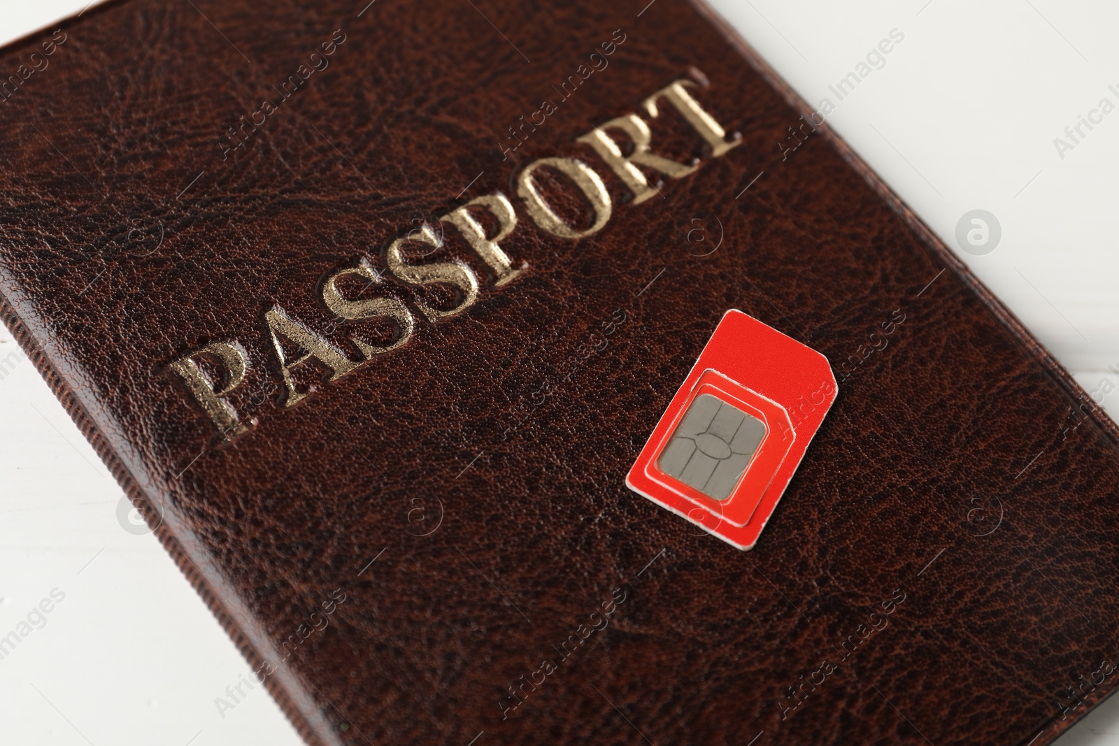 Photo of Passport and SIM card on white table, closeup