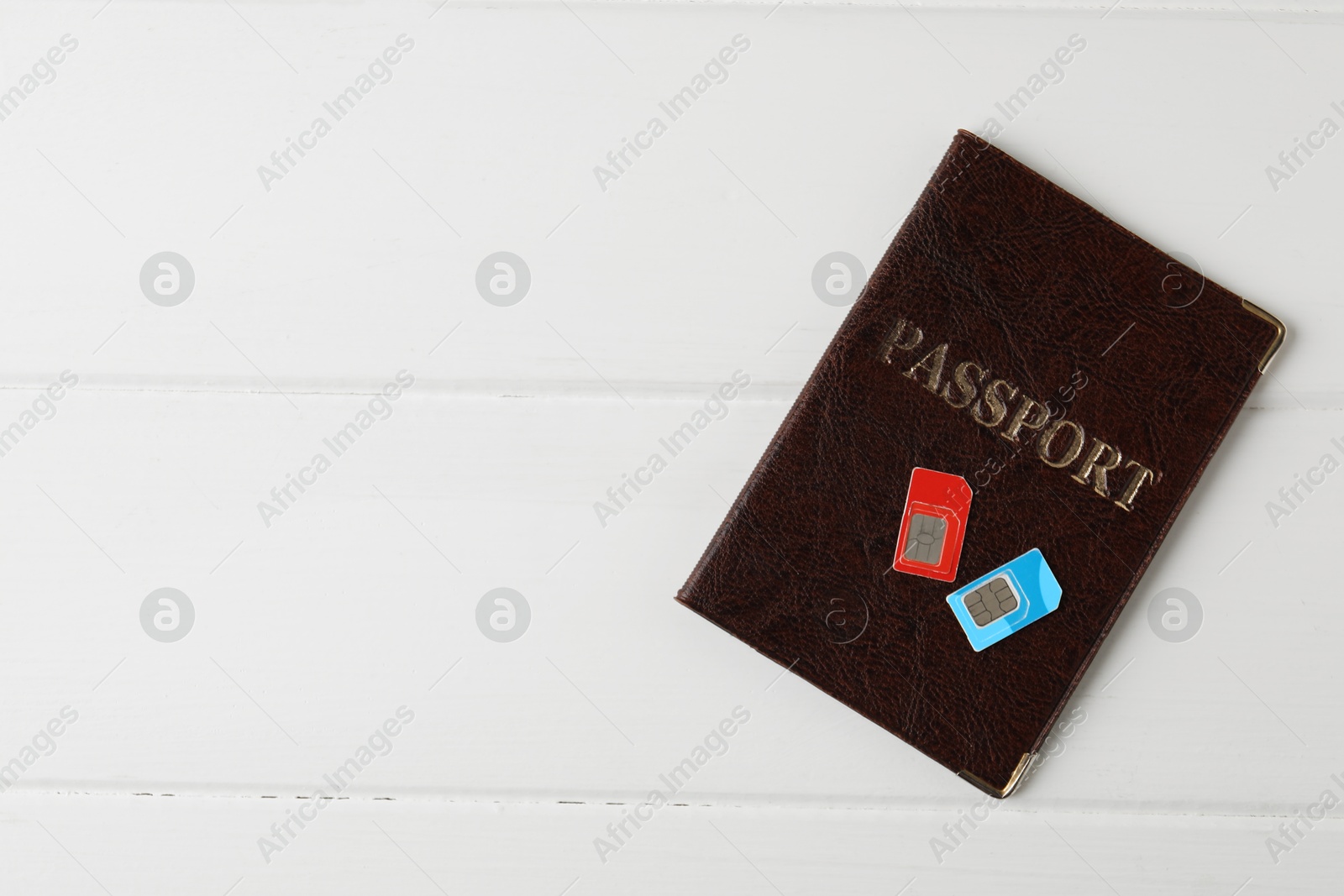 Photo of Passport and SIM cards on white wooden table, top view. Space for text