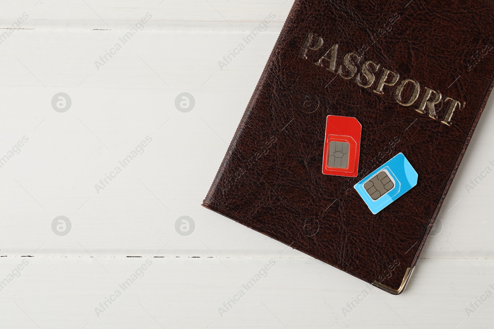 Photo of Passport and SIM cards on white wooden table, top view. Space for text