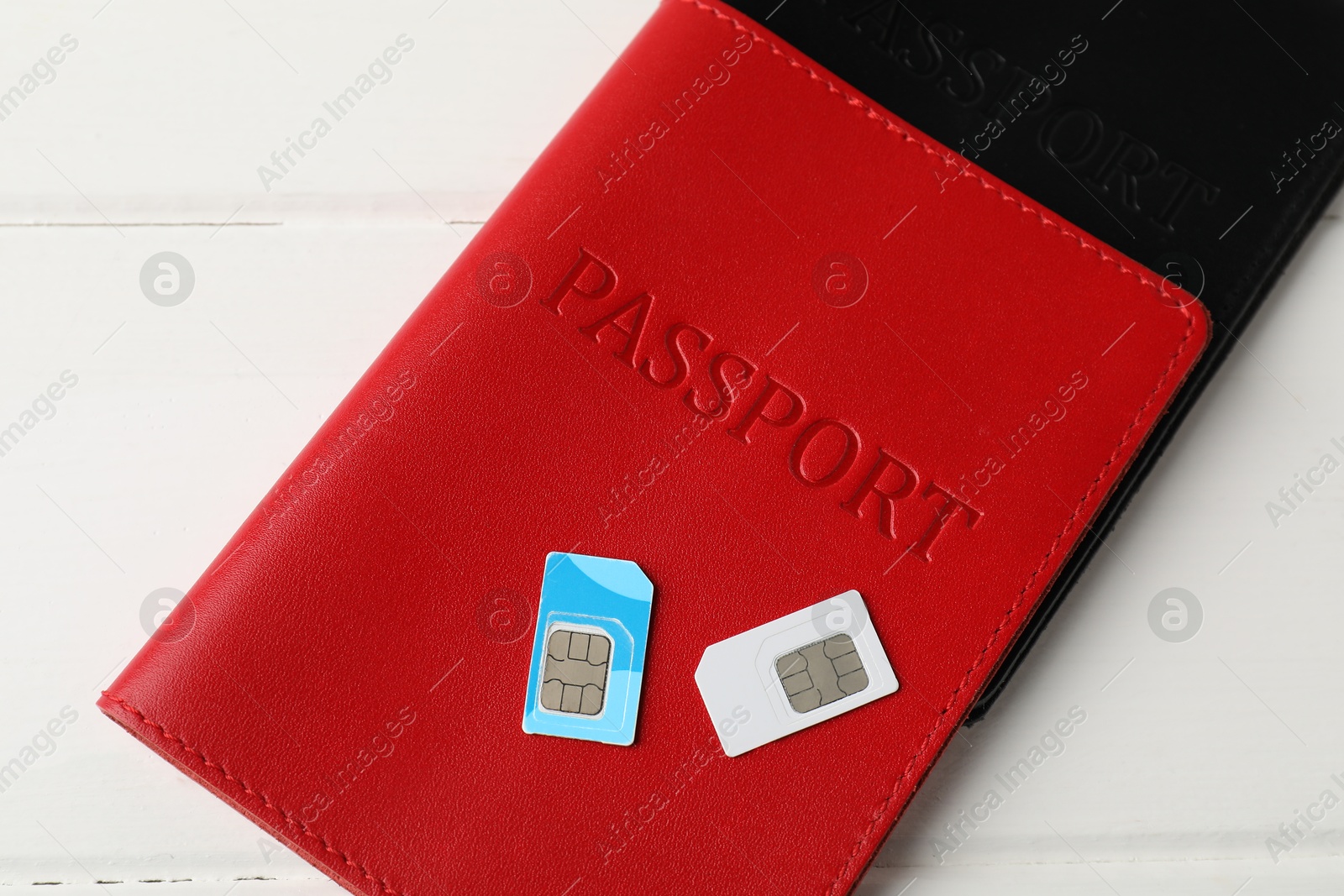 Photo of Passports and SIM cards on white wooden table, flat lay