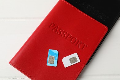 Photo of Passports and SIM cards on white wooden table, flat lay