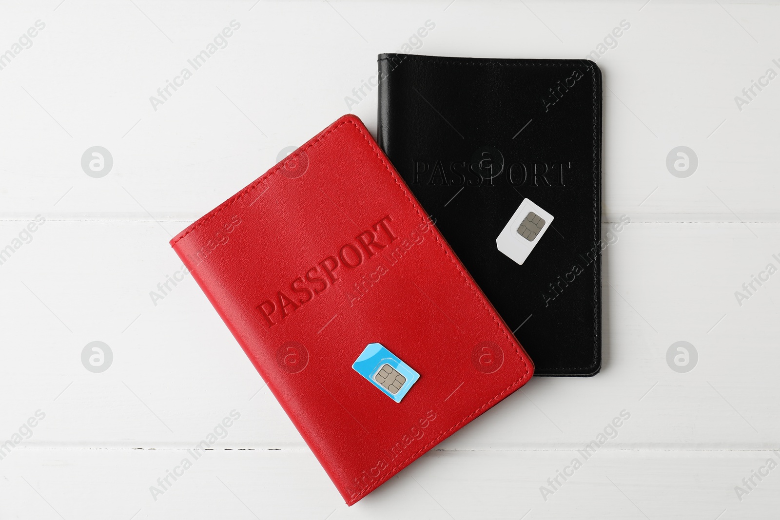 Photo of Passports and SIM cards on white wooden table, flat lay