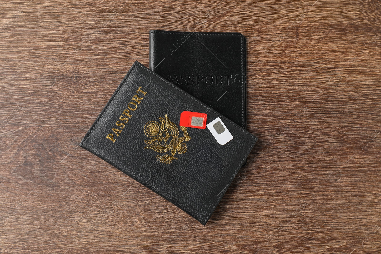 Photo of Passports and SIM cards on wooden table, flat lay