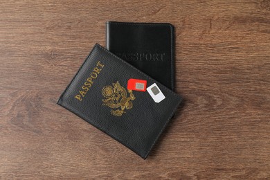 Passports and SIM cards on wooden table, flat lay