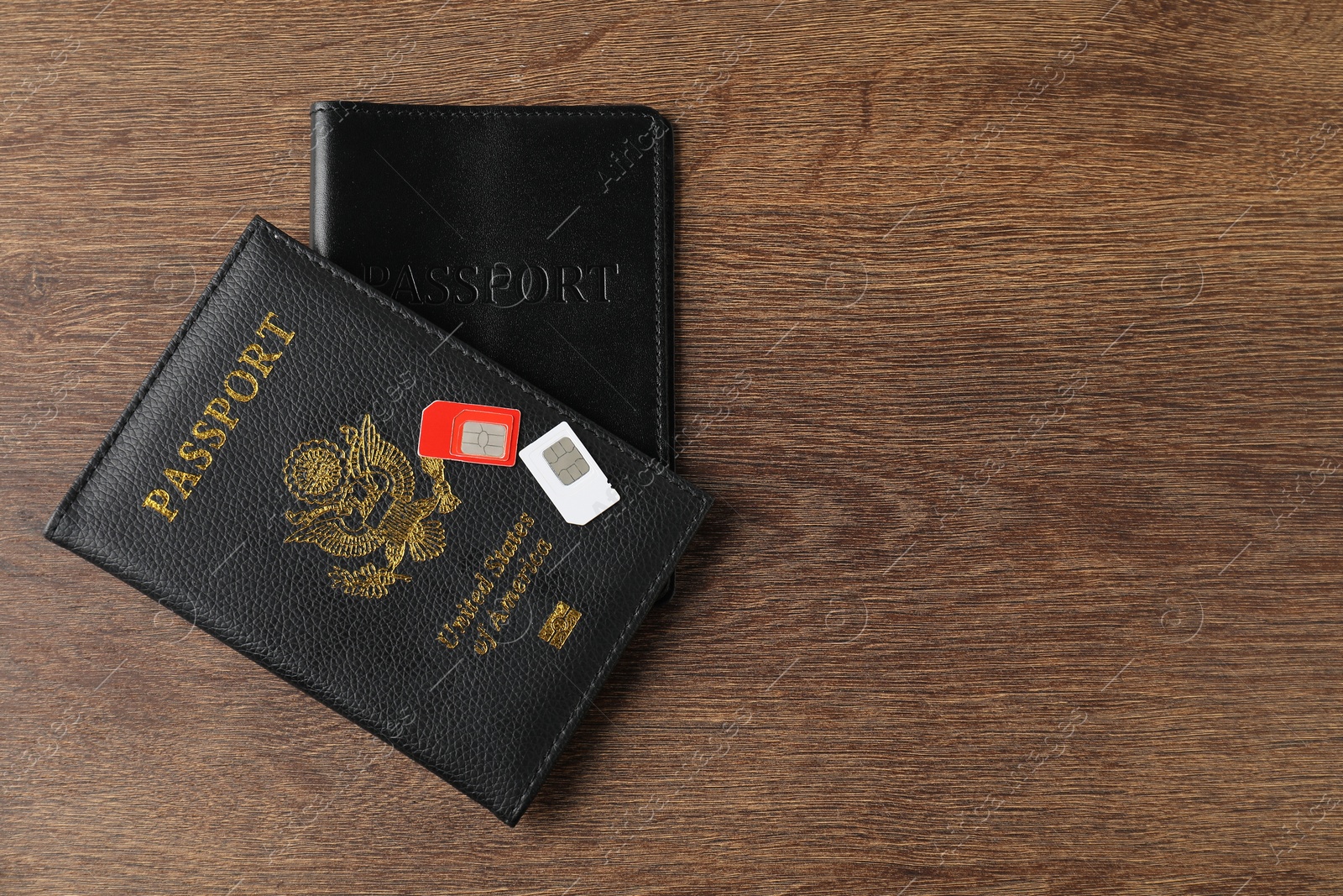 Photo of Passports and SIM cards on wooden table, flat lay. Space for text