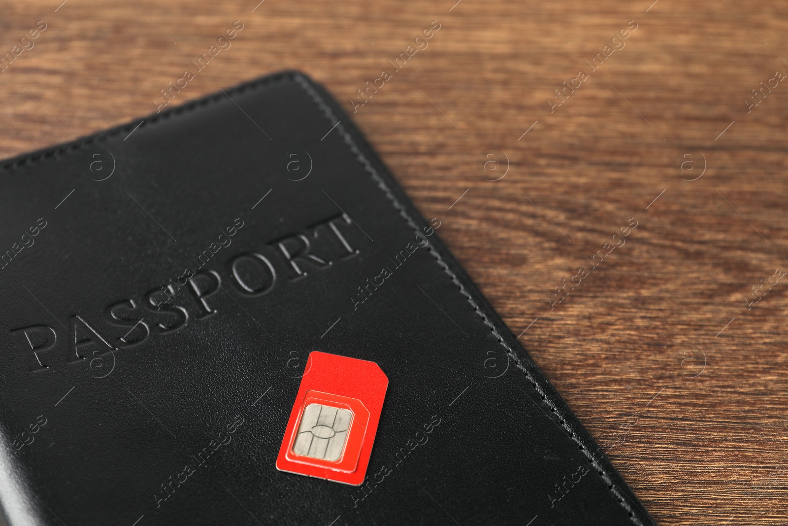 Photo of Passport and SIM card on wooden table, closeup