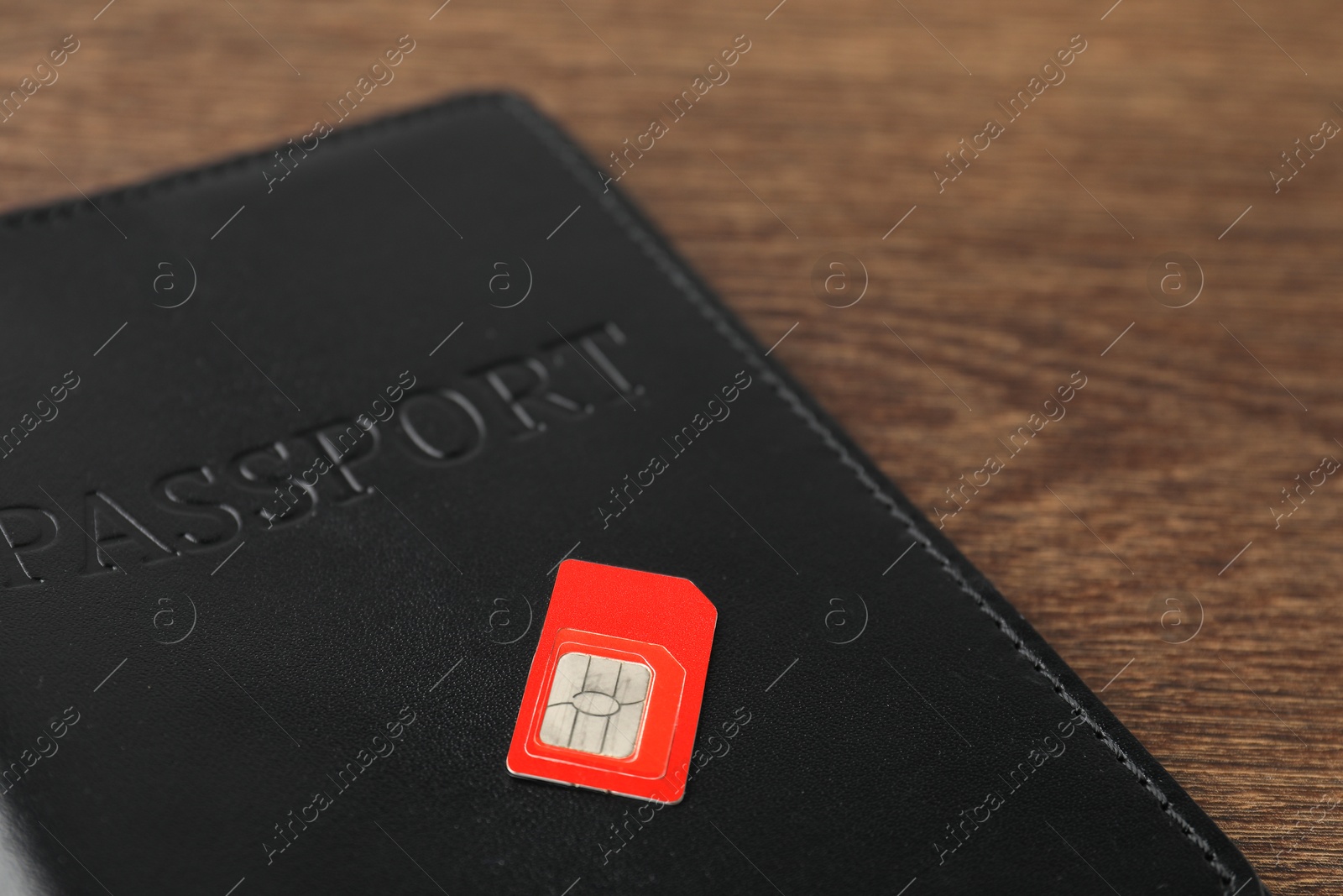 Photo of Passport and SIM card on wooden table, closeup