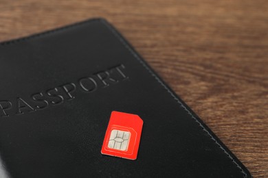 Passport and SIM card on wooden table, closeup