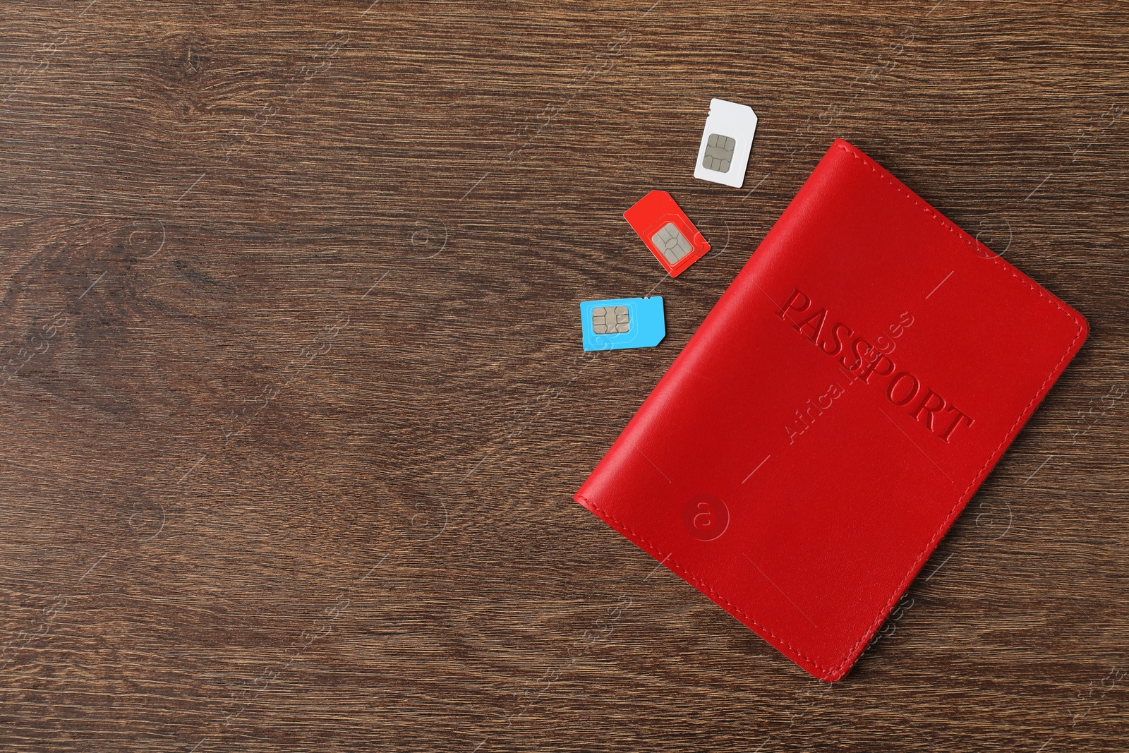 Photo of Passport and SIM cards on wooden table, flat lay. Space for text