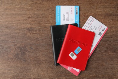 Photo of Passports, tickets and SIM cards on wooden table, flat lay