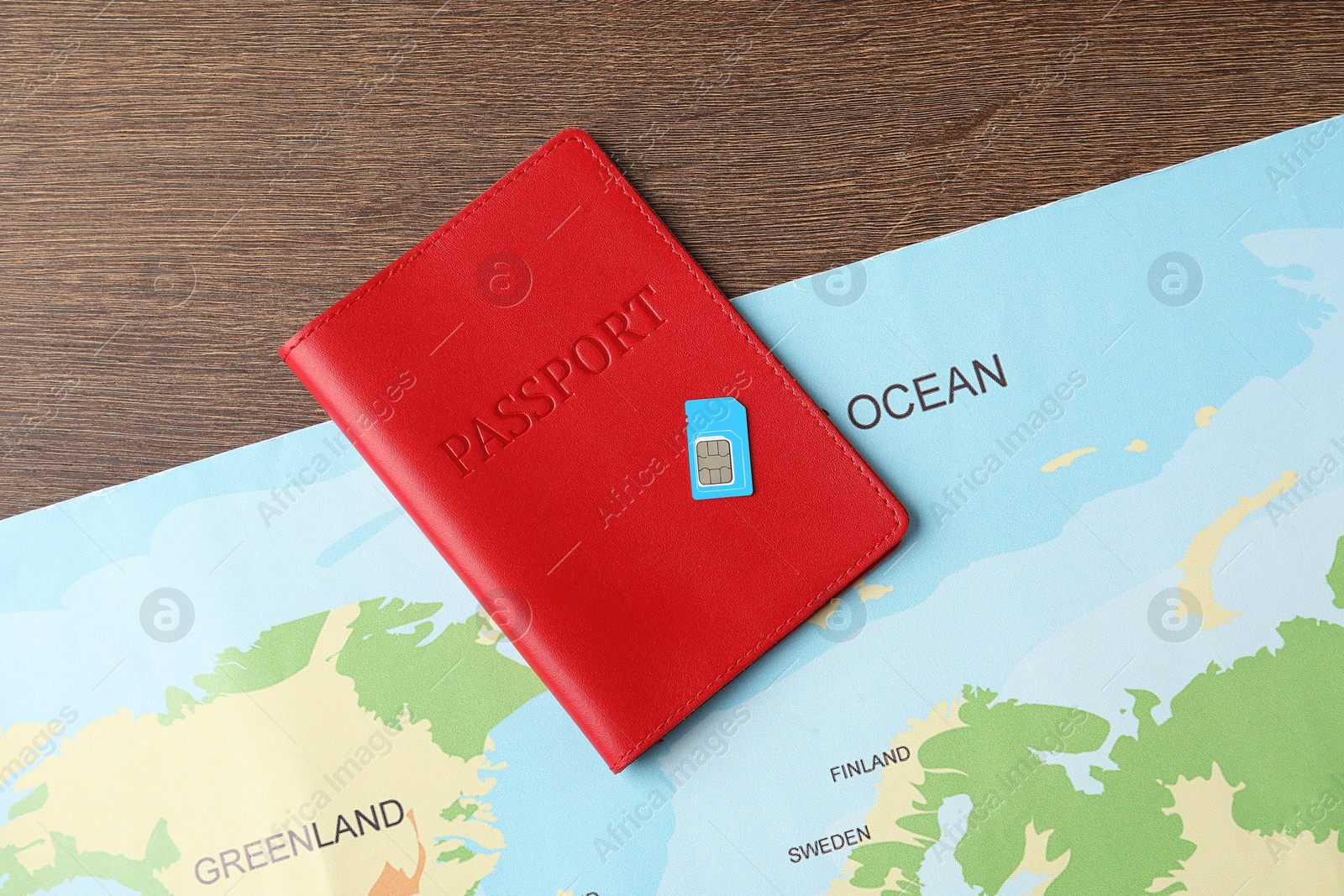 Photo of Passport, world map and SIM card on wooden table, flat lay