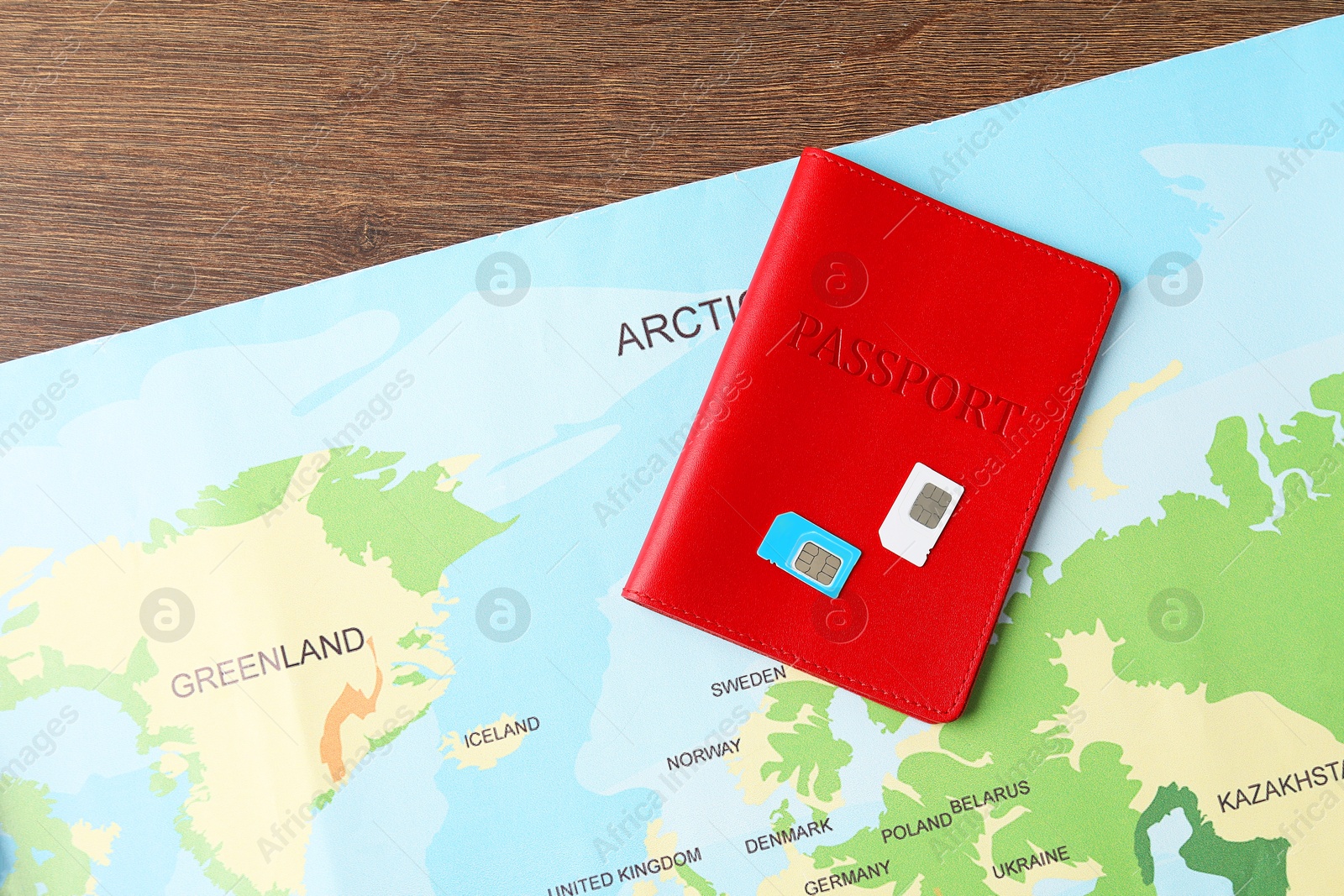 Photo of Passport, world map and SIM cards on wooden table, flat lay