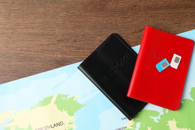 Photo of Passports, world map and SIM cards on wooden table, flat lay