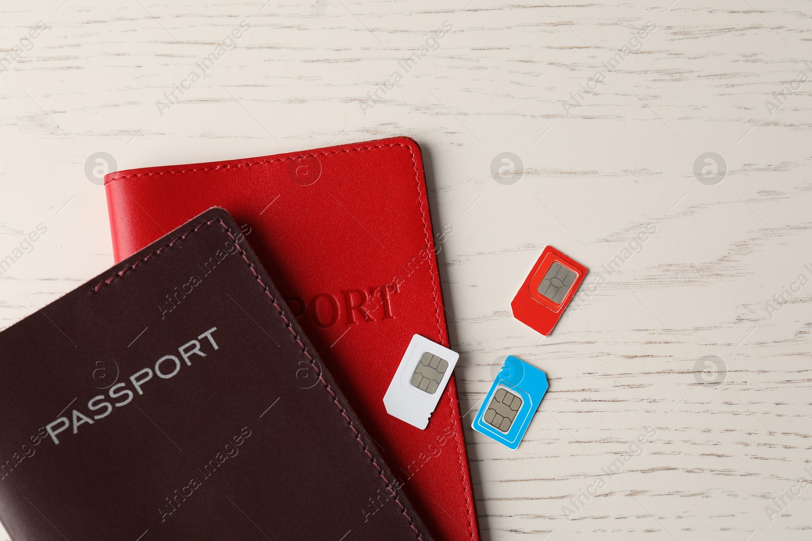 Photo of Passports and SIM cards on white wooden table, flat lay