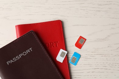 Photo of Passports and SIM cards on white wooden table, flat lay