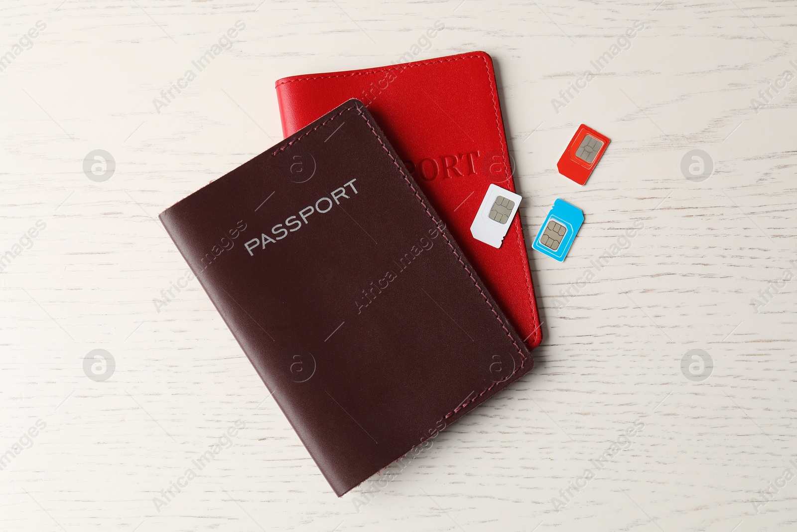 Photo of Passports and SIM cards on white wooden table, flat lay