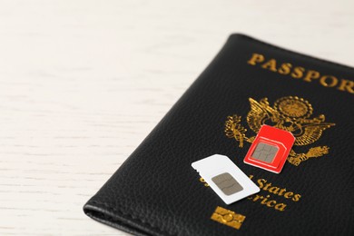 Photo of Passport and SIM cards on white wooden table, closeup. Space for text