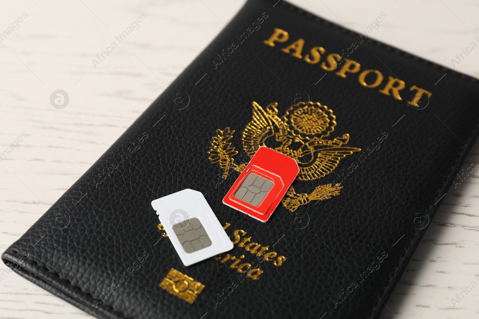 Photo of Passport and SIM cards on white wooden table, closeup