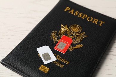 Photo of Passport and SIM cards on white wooden table, closeup