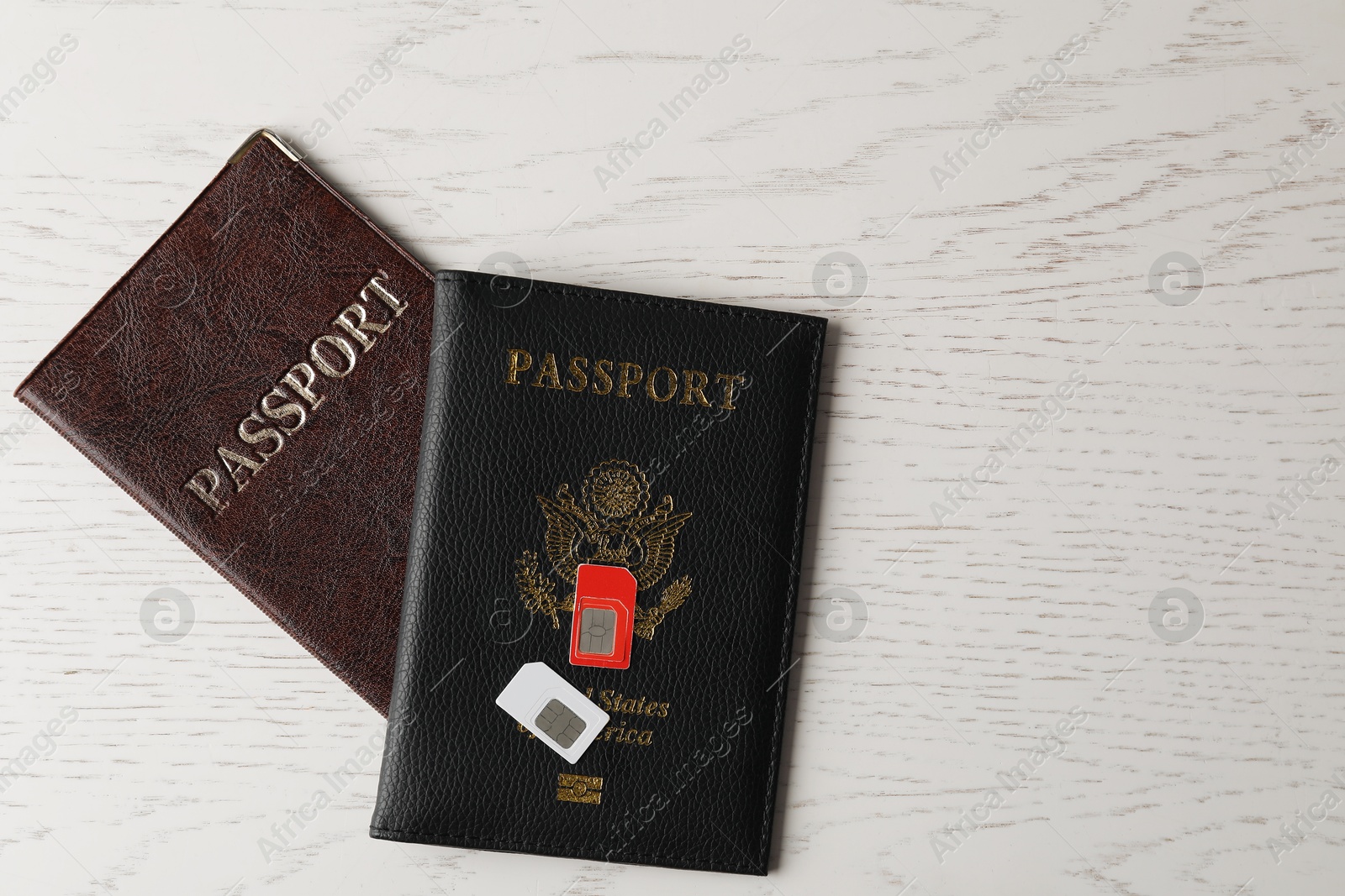 Photo of Passports and SIM cards on white wooden table, flat lay. Space for text