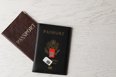 Photo of Passports and SIM cards on white wooden table, flat lay. Space for text