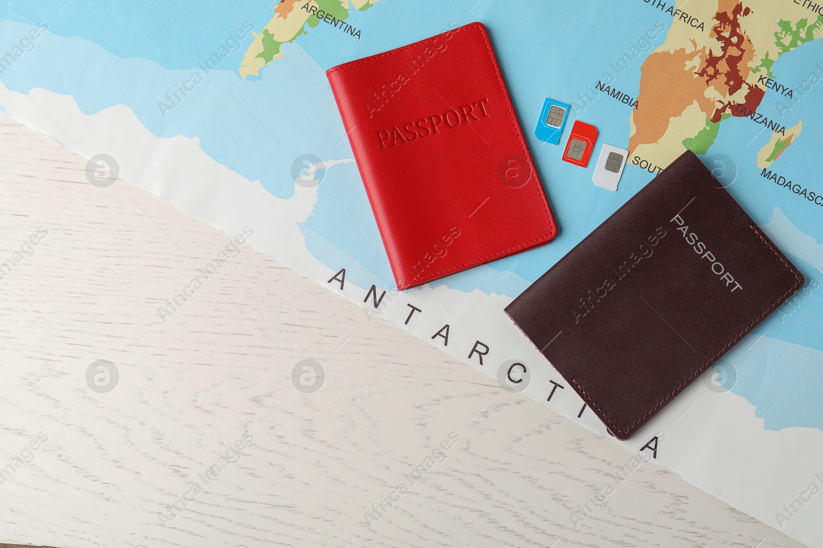 Photo of Passports, world map and SIM cards on white wooden table, flat lay