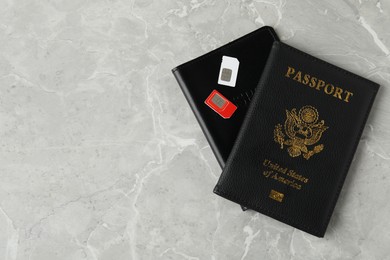 Passports and SIM cards on grey marble table, flat lay. Space for text