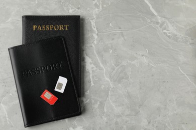 Photo of Passports and SIM cards on grey marble table, flat lay. Space for text