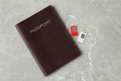 Passport and SIM cards on grey marble table, flat lay