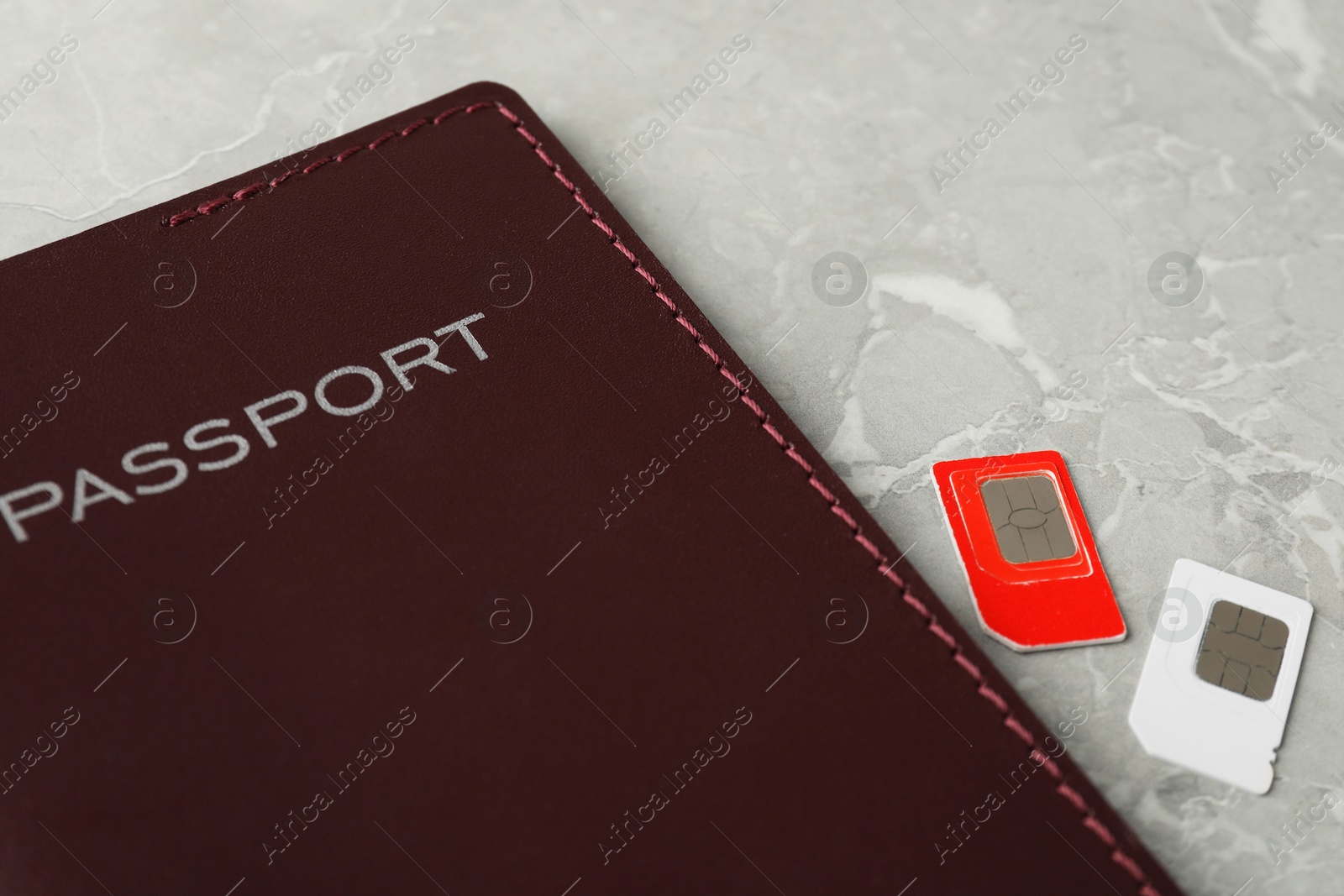 Photo of Passport and SIM cards on grey marble table, closeup