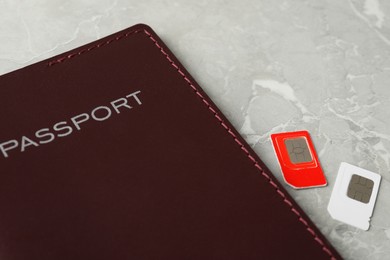 Passport and SIM cards on grey marble table, closeup