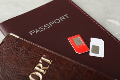 Passports and SIM cards on grey table, closeup