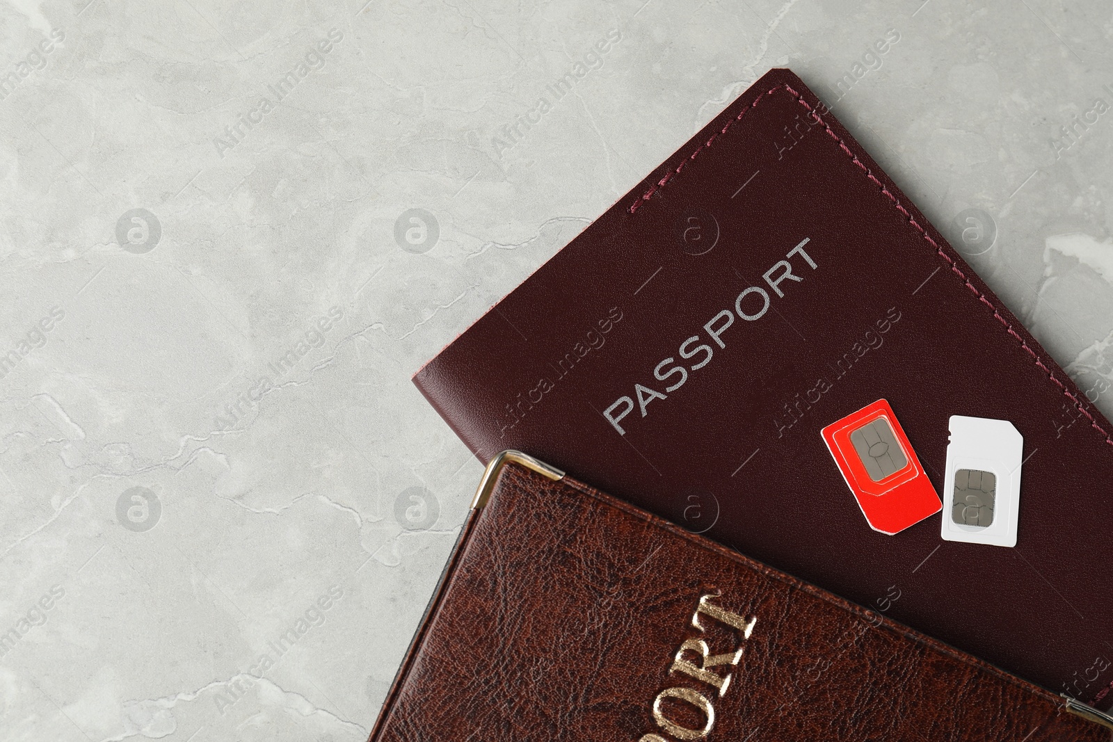 Photo of Passports and SIM cards on grey marble table, flat lay. Space for text